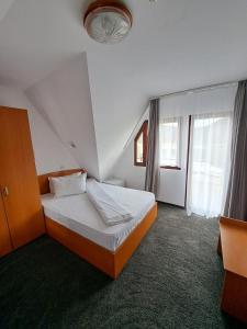 Hotel Pescarus Port Bicaz في بيكاز: غرفة نوم بسرير ونافذة كبيرة