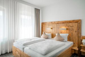 a bedroom with two white beds with a wooden headboard at Manufaktur Boutique Hotel in Stadt Wehlen