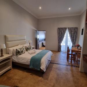a bedroom with a bed and a table and a desk at Journey Guesthouse in Riversdale