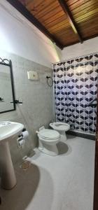 La salle de bains est pourvue de toilettes blanches et d'un lavabo. dans l'établissement Casa de Piedra, à Termas del Daymán