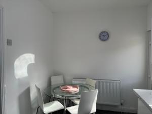 a dining room table with chairs and a clock on the wall at 2 Bed Property with parking in Liverpool
