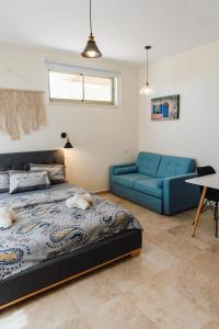 ein Schlafzimmer mit einem Bett und einem blauen Sofa in der Unterkunft אבן על הנחל in Merhav Am
