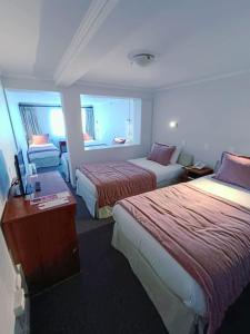 ein Hotelzimmer mit 2 Betten und einem Schreibtisch in der Unterkunft Hotel Nicolás Temuco in Temuco