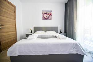 - une chambre avec un grand lit et des draps blancs dans l'établissement Apartament Katrina - Alezzi Beach - Sea View, à Mamaia Nord – Năvodari