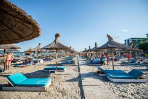 - une plage avec de nombreuses chaises et parasols en paille dans l'établissement Apartament Katrina - Alezzi Beach - Sea View, à Mamaia Nord – Năvodari