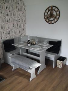 a white table and bench with a clock on the wall at Borrowmoss Bothy, Charming & Characterful property, Wigtown in Wigtown