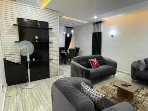 a living room with a couch and a fan at Elimus Apartments & Suites 