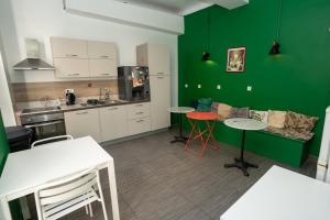 uma cozinha com paredes verdes, mesas e cadeiras em Le Pastoral em Nice