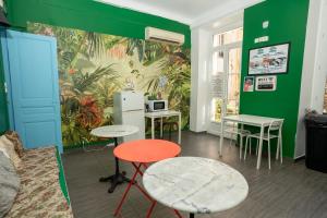 Habitación con mesas, sillas y una pared verde. en Le Pastoral, en Niza