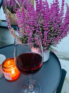 a glass of red wine next to a vase of flowers at Garden Place Apartment in Warsaw