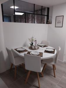 einen Esstisch mit weißen Stühlen, einem weißen Tisch und einem Stuhl in der Unterkunft PRIMO - Logement 4/6 personnes in Braux
