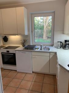 une cuisine avec des armoires blanches, un évier et une fenêtre dans l'établissement Sonniges Garten-Apartment in ruhiger Parklage, à Bad Segeberg 6 autres photos