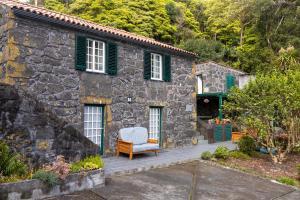 una casa de piedra con una silla blanca en el patio en Casa de Basalto, en Lajes do Pico