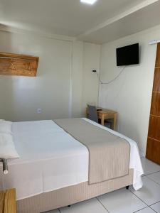 a bedroom with a bed and a tv on the wall at Pousada Maanaim in Campina Grande