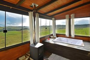 a bath tub in a room with large windows at Chalé Vista do Vale in Cambara do Sul