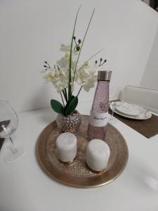 a vase with flowers and a bottle on a plate at PRIMO - Logement 4/6 personnes in Braux