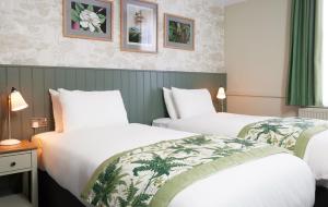 two beds in a hotel room with green curtains at The Kings Head Wroxham by Greene King Inns in Wroxham