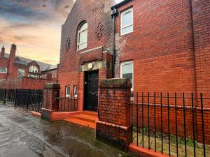 a brick building with a black door and a fence at West End Gem 3BR Detached Family House in Glasgow
