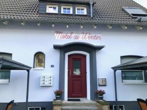 un bâtiment blanc avec une porte rouge et un panneau dans l'établissement Motel de Winter - Motel - Apartmenthaus - Monteurzimmer, à Castrop-Rauxel