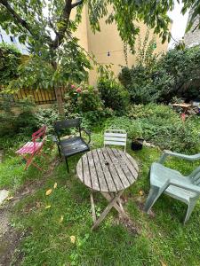 3 chaises et une table en bois dans l'herbe dans l'établissement Charming Apartment in Paris, à Bagnolet