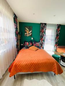 Schlafzimmer mit orangefarbenem Bett und grünen Wänden in der Unterkunft Apartament U Bartusia in Zakopane