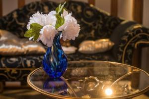 um vaso azul com flores brancas sobre uma mesa em La Rose Médiévale Balnéo & Sauna em Domfront