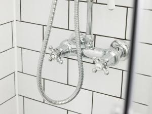 a shower head on a white tiled wall at The Kings Head Wroxham by Greene King Inns in Wroxham