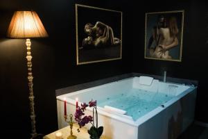 ein Badezimmer mit einer Badewanne, einer Lampe und Bildern in der Unterkunft La Rose Médiévale Balnéo & Sauna in Domfront