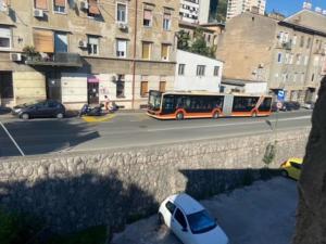a bus driving down a city street with a white car at Apartman Mila - free parking and WiFi in Rijeka