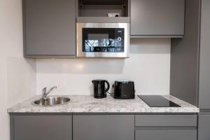 a kitchen counter with a sink and a microwave at Sleek and Stylish Studio: Old Trafford in Manchester
