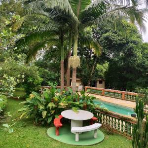 een tafel en stoelen in een tuin met een zwembad bij Sítio charmoso in Jarinu
