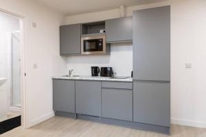 eine Küche mit grauen Schränken und einer Mikrowelle in der Unterkunft Sleek and Stylish Studio: Old Trafford in Manchester