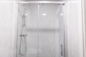 ein Bad mit einer Dusche und einer Glastür in der Unterkunft Sleek and Stylish Studio: Old Trafford in Manchester