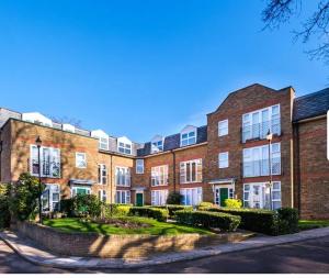 un gran edificio de ladrillo con un jardín delante de él en Stunning 1-Bed Apartment close to Hotspur, en Enfield