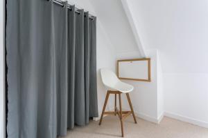 una sedia in una stanza con tende grigie di Le Dériveur - 3 chambres - Jardin et terrasse a Saint-Lunaire