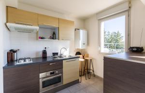 a kitchen with wooden cabinets and a sink and a window at La Rossa proche métro parking privé in Rennes
