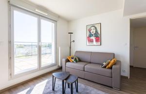 a living room with a couch and a large window at La Rossa proche métro parking privé in Rennes