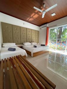 a bedroom with two beds and a large window at Huvan Inn in Fulidhoo