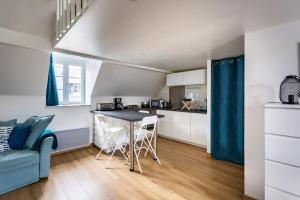 een keuken en een woonkamer met een tafel en een bank bij Le Petit Pastel - Joli duplex - Proche de la plage in Saint-Malo