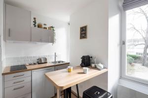 cocina con armarios blancos y mesa de madera en L'éden studio moderne et lumineux proche centre, en Rennes
