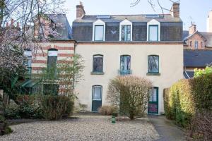 Casa blanca grande con puertas y ventanas verdes en L'éden studio moderne et lumineux proche centre, en Rennes