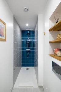 y baño con ducha de azulejos azules. en L'éden studio moderne et lumineux proche centre, en Rennes