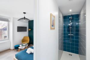 y baño con ducha y pared de azulejos azules. en L'éden studio moderne et lumineux proche centre, en Rennes