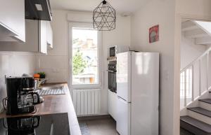 uma cozinha com um frigorífico branco e uma janela em Le Gardelle - Jolie maison de ville (2 chambres) em Saint Malo