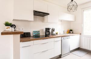 a white kitchen with white cabinets and a counter top at Le Gardelle - Jolie maison de ville (2 chambres) in Saint Malo