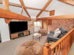 a living room with a tv and a brick wall at The Hideaway Waverton Villa in Wigton