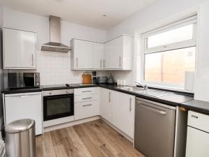 a white kitchen with white cabinets and a window at 46 The Promenade in Withernsea