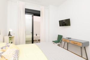 een slaapkamer met een bed, een bureau en een televisie bij Loving Rota in Rota
