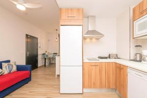 een keuken met een rode bank en een witte koelkast bij Loving Rota in Rota
