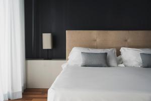 una camera da letto con un grande letto con lenzuola e cuscini bianchi di The Regent Boutique Hotel & Spa PRE OPENING a San Marino